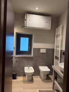 un bagno con lavandino, WC e finestra di Lanzo Belvedere - Central Apartment a Lanzo Torinese