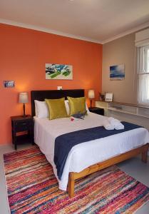 ein Schlafzimmer mit einem großen Bett mit einer orangefarbenen Wand in der Unterkunft Penn's Place in Muizenberg