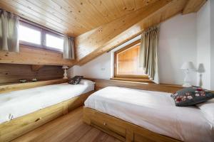 two beds in a log cabin bedroom with wooden walls at Chalet Lacedel - Dolomiti Skyline in Cortina dʼAmpezzo