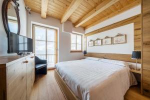 a bedroom with a bed and a flat screen tv at Chalet Lacedel - Dolomiti Skyline in Cortina dʼAmpezzo