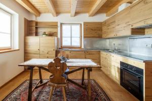 a kitchen with wooden walls and a wooden table with a chair at Chalet Lacedel - Dolomiti Skyline in Cortina dʼAmpezzo +7 photos