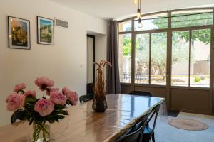 une table à manger avec des fleurs roses dans un vase dans l'établissement Bastide des Oliviers, Maison Provençale, à Boulbon