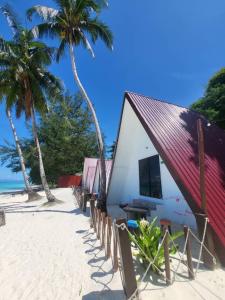 ein kleines Gebäude am Strand mit Palmen in der Unterkunft DEWATI ROOMSTAY B&B in Lang Tengah
