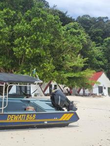 ein blaues und gelbes Boot am Strand in der Unterkunft DEWATI ROOMSTAY B&B in Lang Tengah