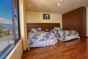 a bedroom with two beds and a large window at Hotel Portugal Confort in Ambato