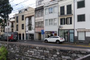 een witte auto geparkeerd in een stadsstraat met gebouwen bij Residência Lord Freitas I by An Island Apart in Funchal +2 foto's