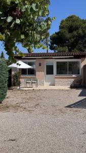 a house with a table and an umbrella in front of it at Studio en Provence in Cheval-Blanc