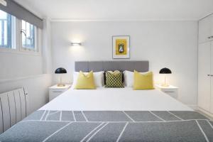 - une chambre blanche avec un grand lit et des oreillers jaunes dans l'établissement Camden Serviced Apartments by Globe Apartments, à Londres