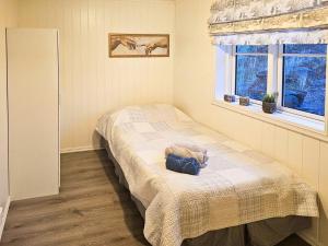 Un dormitorio con una cama con una manta y una ventana. en Charming Farm Stay On Averøy Island, en Lyngstad