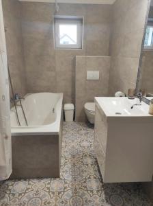 a bathroom with a tub and a sink and a toilet at Golden Home Törökbálint in Törökbálint