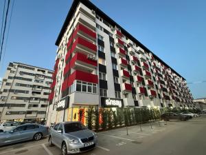 a red and white building with cars parked in a parking lot at Garsonieră Studio in Dudu