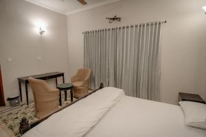 een slaapkamer met een bed, stoelen en een raam bij The Heritage in Jodhpur