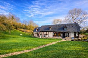 a large house on a grassy field in front at Le Hameau des Prés-Verts, un séjour détente et bien être pour les amoureux de la nature au cœur du Pays d'Auge, en Normandie in Les Champeaux