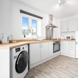a kitchen with white cabinets and a washer and dryer at Modern Two Bed Apartment - Sleeps 3 - WiFi & Parking Included 57C in Sleightholme