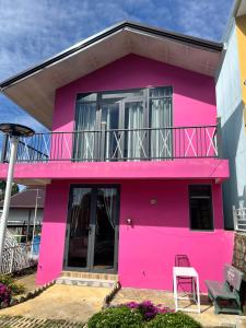 a pink house with a balcony and a chair at Mia Homestay and Coffee in Bảo Lộc