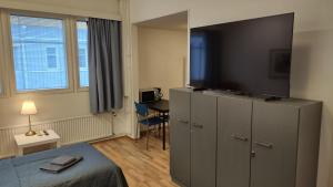 una camera d'albergo con TV a schermo piatto in cima a un armadio di Hotel 24 - Apartments a Kemi
