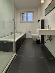 a bathroom with a tub and a sink and a toilet at HAVENU Ludwigsburg Mitte in Ludwigsburg