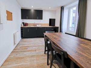 eine Küche mit einem Holztisch und schwarzen Schränken in der Unterkunft Vert Bocage Briard - Freedomus Marne-la-Vallée in Esbly + 6 Fotos