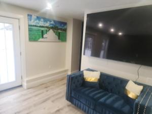 een woonkamer met een blauwe bank en een flatscreen-tv bij Modern Basement Suite • King Bed & 100” TV in Shrewsbury