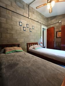 zwei Betten in einem Zimmer mit einer Ziegelwand in der Unterkunft El Algarrobo Casa de campo en Cabalango in Cavalango