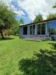 ein Haus mit Fenstern und einem grasbewachsenen Hof in der Unterkunft El Algarrobo Casa de campo en Cabalango in Cavalango