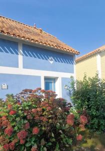 una casa blu e bianca con un cespuglio fiorito di Maisonnette duplex 4 pers proche mer et golf a Talmont