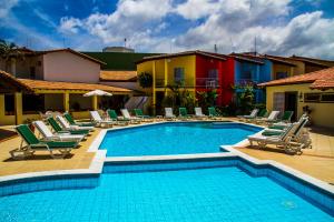 uma piscina com espreguiçadeiras e espreguiçadeiras ao lado de um edifício em Happy Hotel Girassol em Porto Seguro