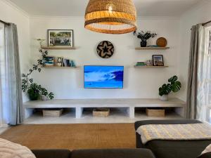 een woonkamer met een tv aan de muur bij Kommetjie Mountain Oasis in Kommetjie