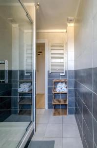 um banheiro com chuveiro e azulejos azuis em L'Oscar Imperial em Compiègne