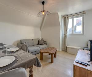 uma sala de estar com um sofá e um lavatório em L'Oscar Imperial em Compiègne