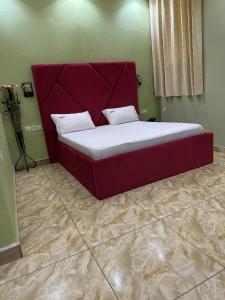 un lit avec tête de lit rouge dans une chambre dans l'établissement HOTEL COMFORT INN & SUITEs, à Yaoundé
