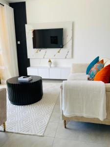 un salon avec un canapé et une télévision fixée au mur dans l'établissement Coral Sands - BriSta Stays, à Mombasa