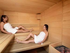 two women are sitting in a sauna at ibis Styles Bialystok in Białystok