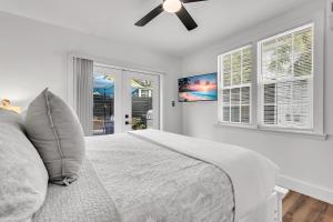 a white bedroom with a bed and a ceiling fan at La Barra #101 in St. Pete Beach