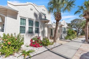 a white house with palm trees and a sidewalk at La Barra #101 in St. Pete Beach