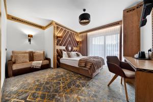a hotel room with a bed and a chair and a desk at Grand Regle Resort & SPA in Poronin