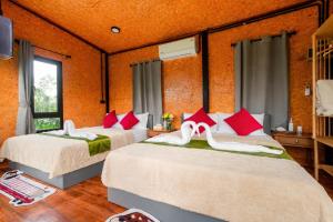 two beds in a room with red and white pillows at ภูธาราทรีเฮาส์แอทเชี่ยวหลาน Phutara Treehouses At Cheowlan in Ban Pha Saeng Lang