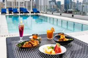 a table with food and drinks next to a pool at Radisson Hotel Chateau de Bangkok in Bangkok