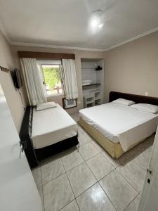 una camera da letto con due letti e una televisione di Amarilis Flat Service a Riviera de São Lourenço