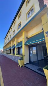 un edificio giallo con una panchina davanti di Hotel Araucano a Mar de Ajó