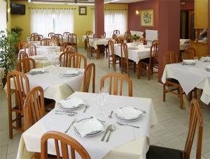 ein Esszimmer mit weißen Tischen und Holzstühlen in der Unterkunft Hotel Restaurante el Fornon in Novellana