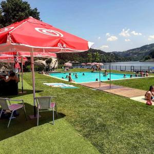 ein Pool mit einem roten Sonnenschirm und Menschen im Wasser in der Unterkunft Quinta do Olival - Douro Valley in Sande
