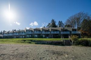een groot huis aan het strand met de zon erachter bij Shorewater Resort, Qualicum Beach in Qualicum Beach