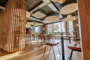 Un restaurante con mesas y sillas de madera y grandes ventanales. en Hôtel AKENA Chalons-en-Champagne, en Châlons-en-Champagne