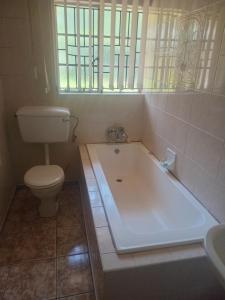 a bathroom with a tub and a toilet and a sink at Sleep Well in Amanzimtoti