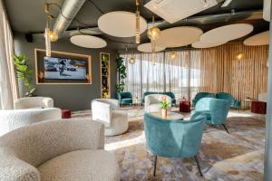 Un vestíbulo con sofás y sillas y un televisor. en Hôtel AKENA Chalons-en-Champagne, en Châlons-en-Champagne