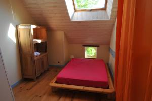 ein kleines Schlafzimmer mit einem roten Bett im Dachgeschoss in der Unterkunft Gîte Erziwezh in La Porte