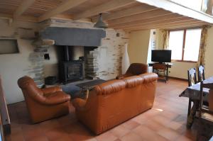 ein Wohnzimmer mit Ledermöbeln und Kamin in der Unterkunft Gîte Erziwezh in La Porte