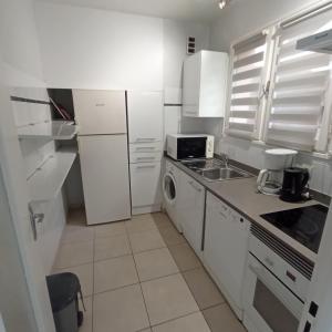 La cuisine blanche est équipée d'un évier et d'un réfrigérateur. dans l'établissement 4HC65 Appartement avec vue sur baie de Collioure, à Collioure