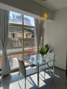 ein Esszimmer mit einem Glastisch und Stühlen und einem großen Fenster in der Unterkunft Urban Opulence in Bangalore